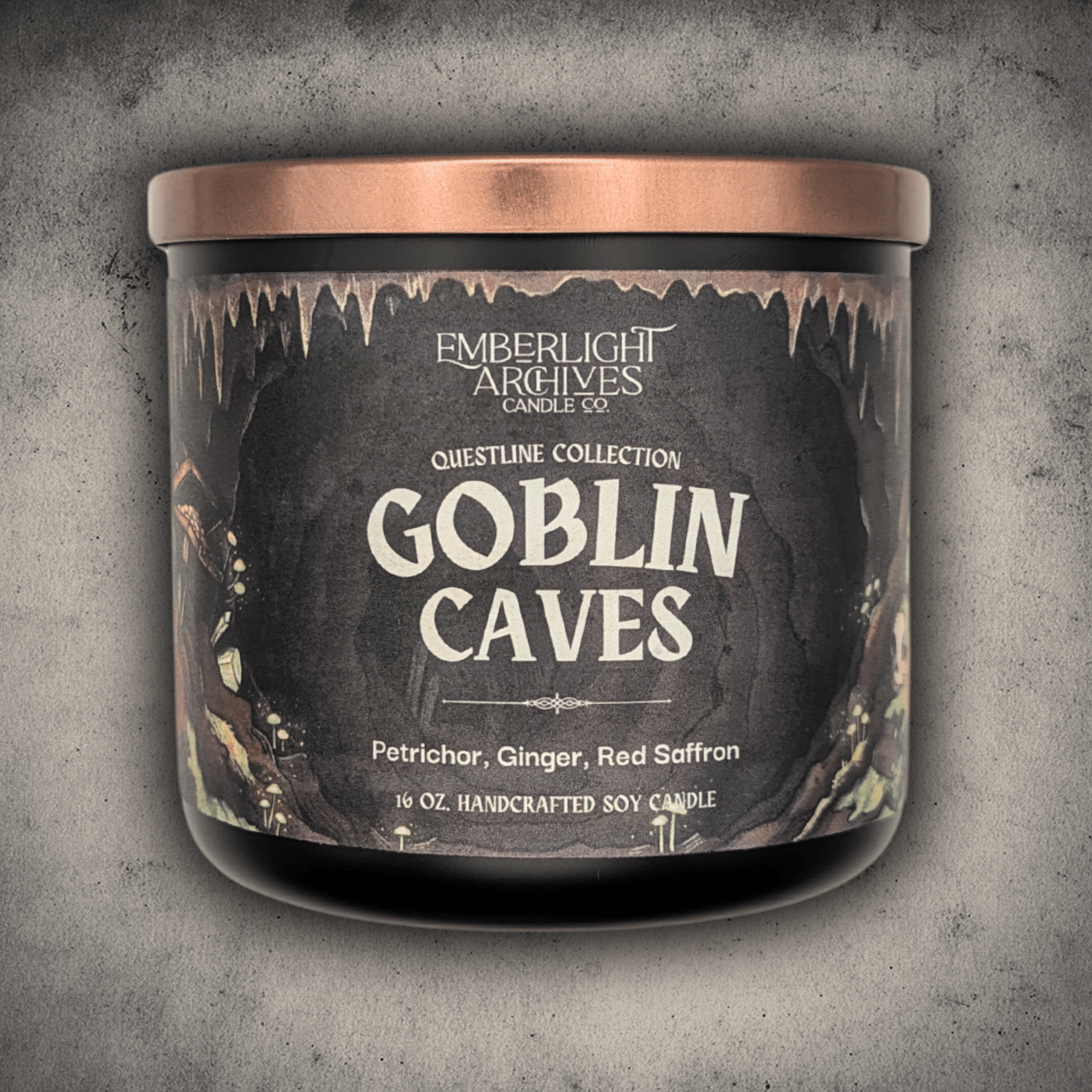 Emberlight Archives Goblin Caves candle in a 16oz black glass jar with illustrated cave label against a gray stone background, Petrichor and Ginger scent.